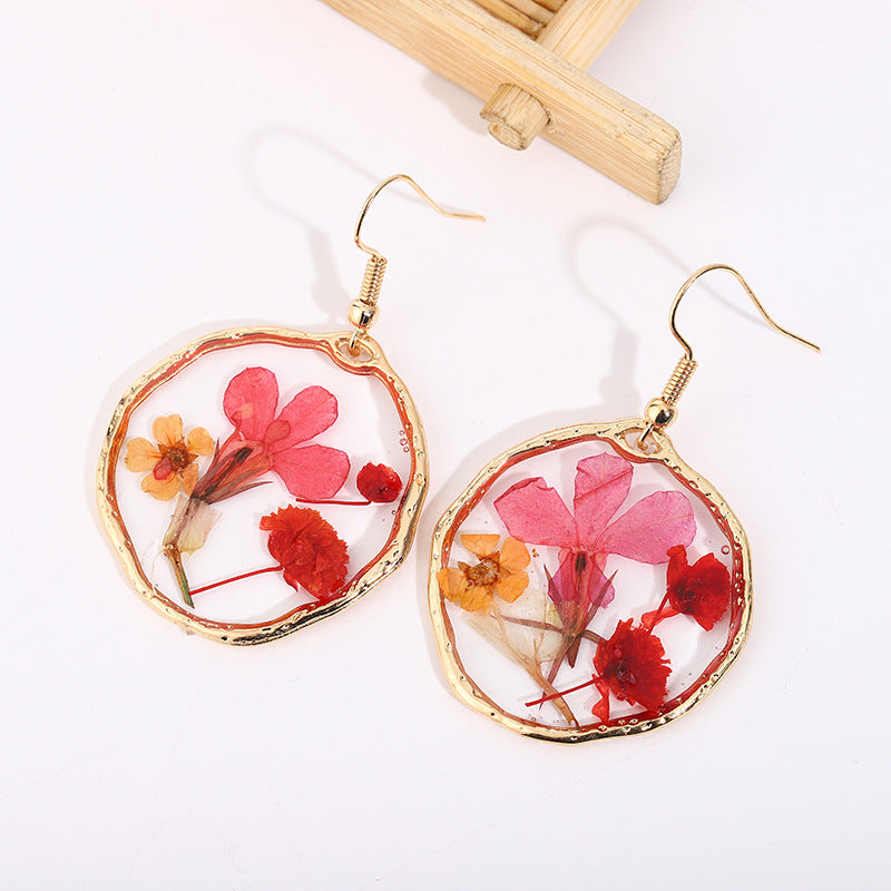 Pendientes de oro con flores secas y pegamento