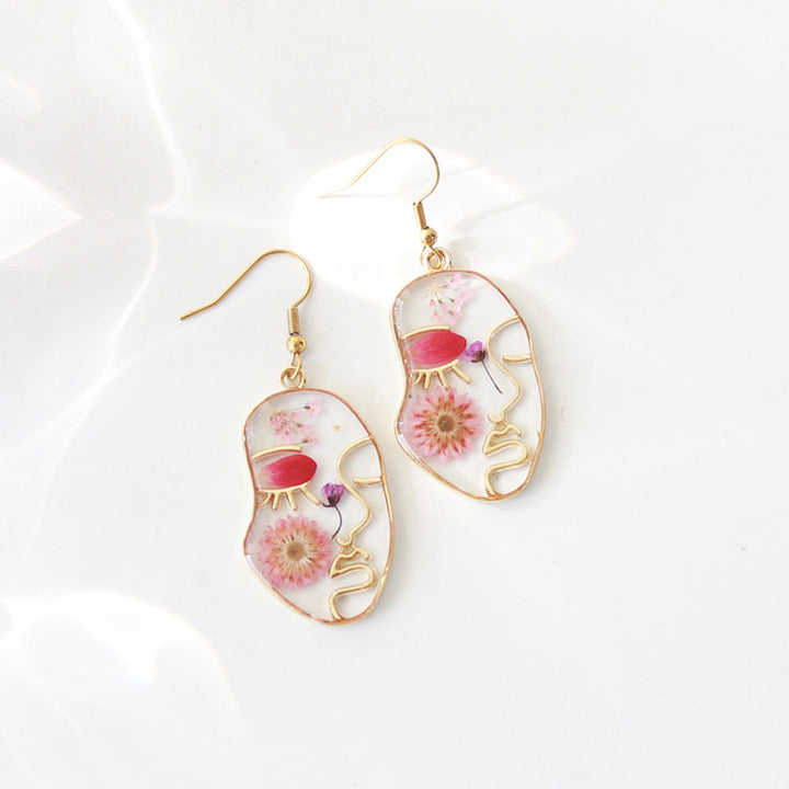 Boucles d'oreilles à fleurs séchées avec visage abstrait