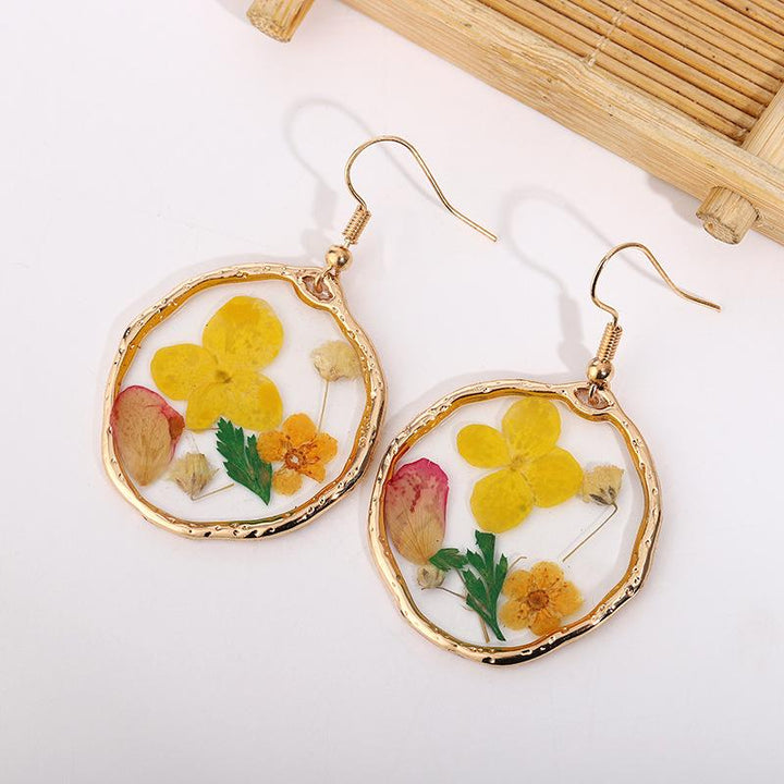 Pendientes de oro con flores secas y pegamento